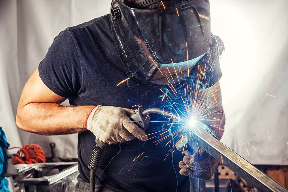 man in black shirt welding in the garage