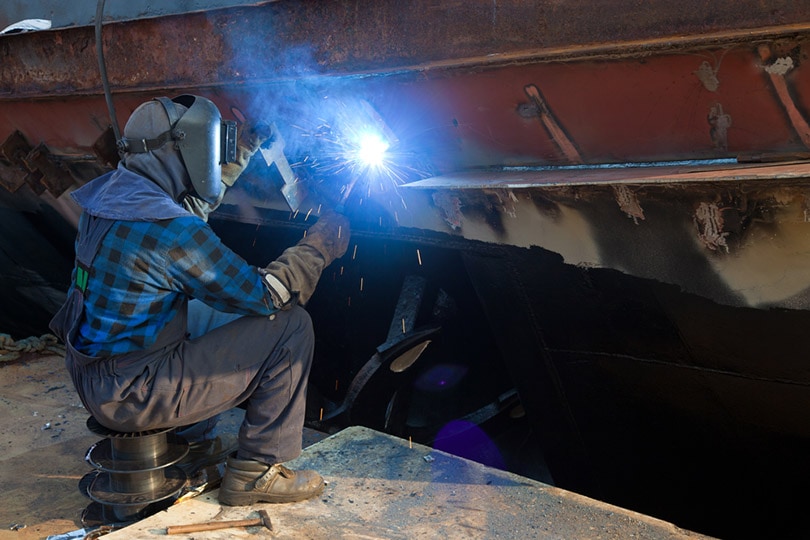 welder repairing ship using arc welding