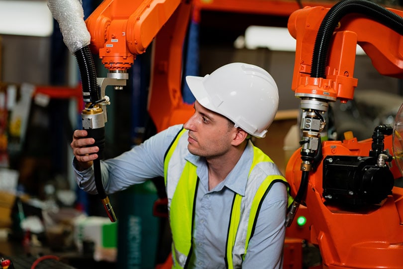 welding engineer is holding a welding robot