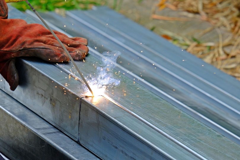 worker welding zinc steel bars