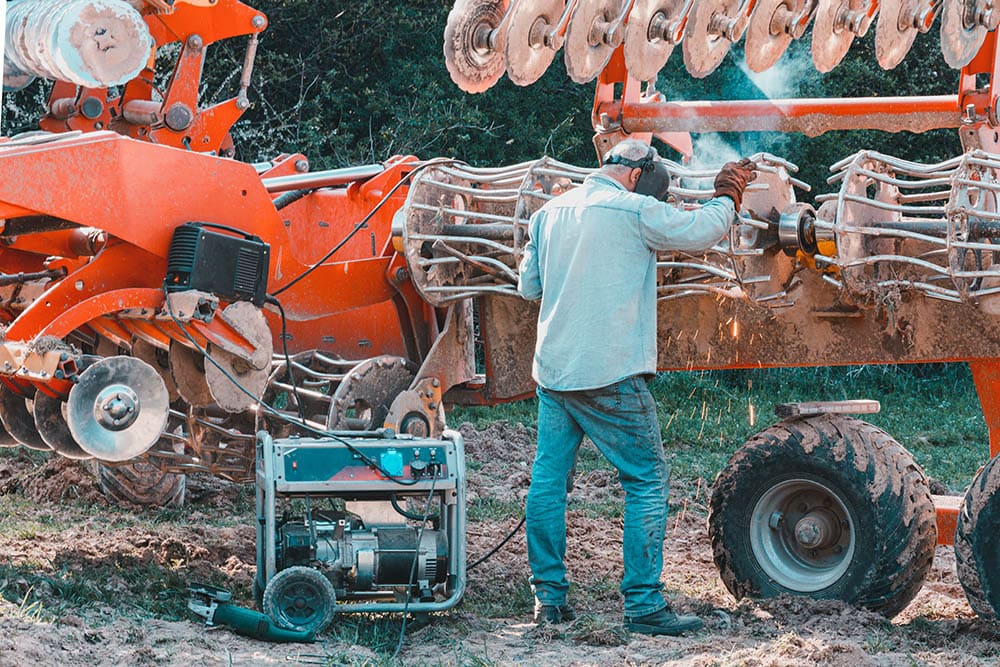 farmer welding the harrows