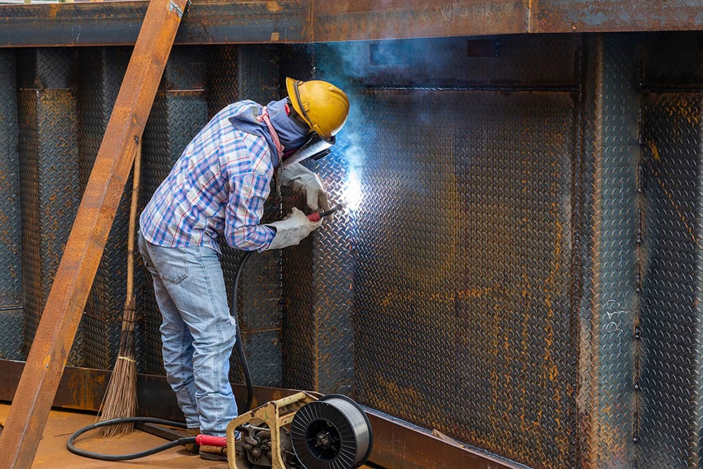 FCAW Vs MIG Welding Differences When To Use Them WaterWelders   Welder Doing FCAW On Steel Structure Thaweesak Thipphamon Shutterstock 